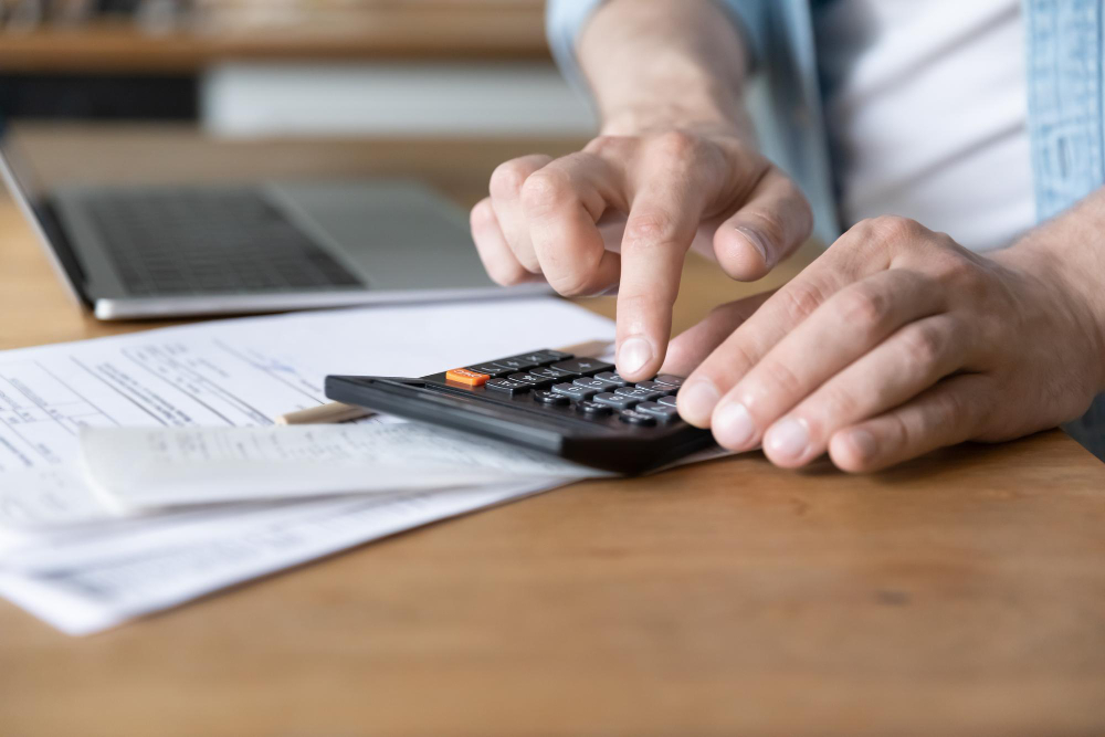 Person calculating expenses with bills and a calculator